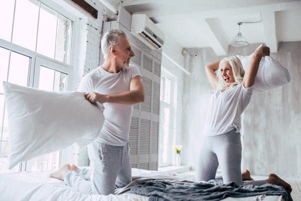 relationship-midlife-crisis midlife couple having a pillow fight during a midlife crisis
